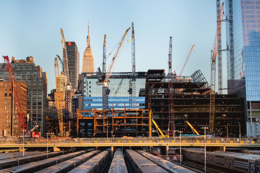 tall buildings under construction and cranes under a blue sky in New York City