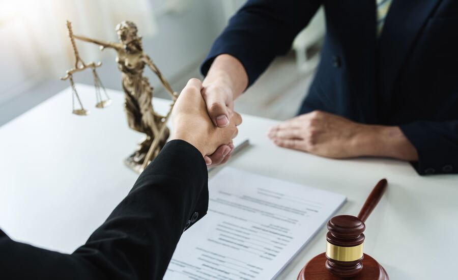 A lawyer and a client shake hands after a successfully resolved negligence case
