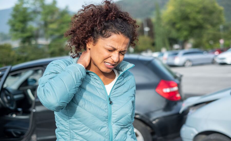 A woman in pain checks her neck for injury after a car accident