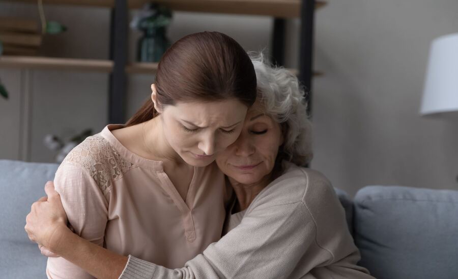 A young woman comforted by her mother