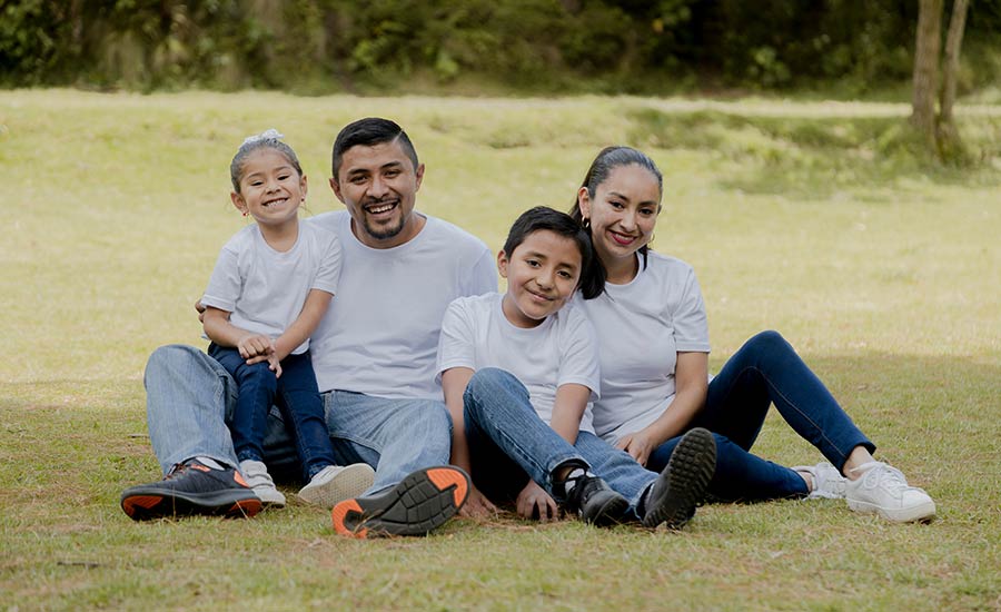 A happy Hispanic family with kids sitting on the grass