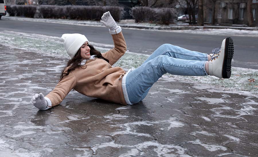 A young woman fallen on slippery icy sidewalk