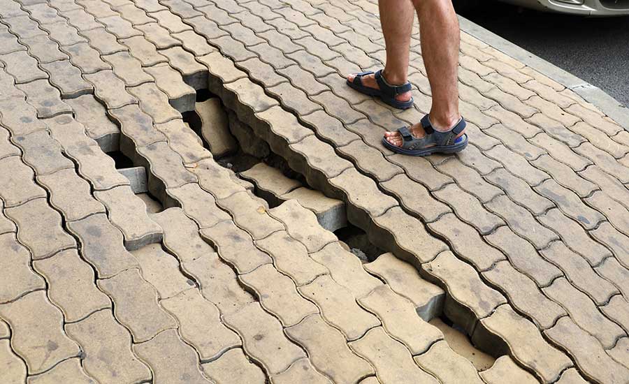 A damaged sidewalk with collapsed road stones