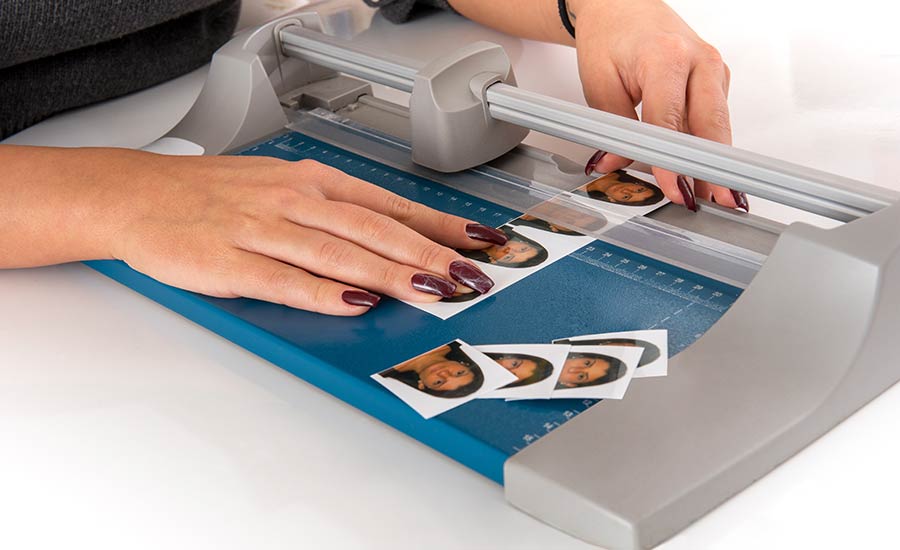 A woman in a photo studio cutting and sizing passport photos​