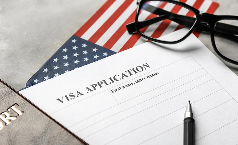 A visa application form next to the U.S. flag