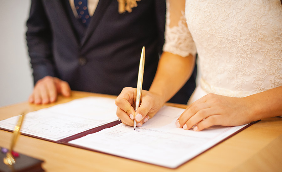 A couple signing documents during a wedding​