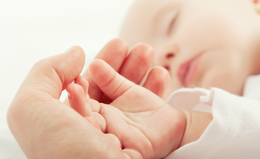 A newborn holding their mother's hand​