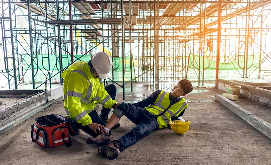 A person is giving first aid to a construction worker who injured his ankle at a construction site​