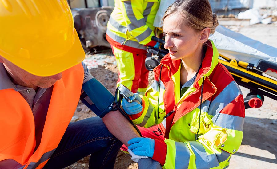 A paramedic measuring a construction worker's blood pressure after an accident​
