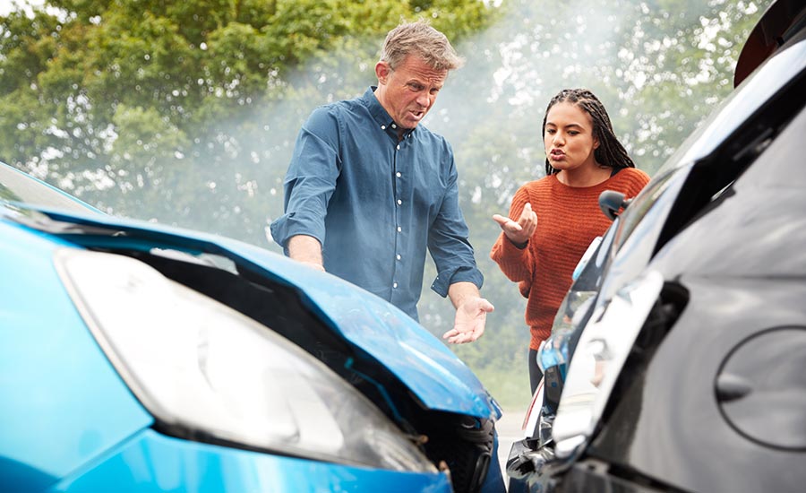 A Man and a woman next to their cars after a collision