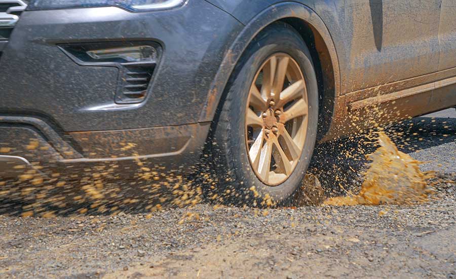 A car hits a pothole splashing muddy water​