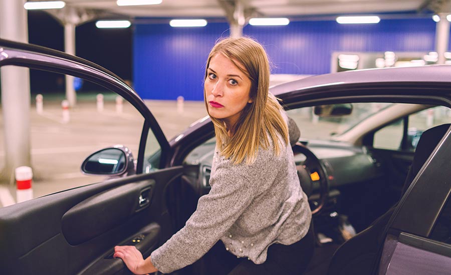 A woman getting out of a parked car in a parking lot​