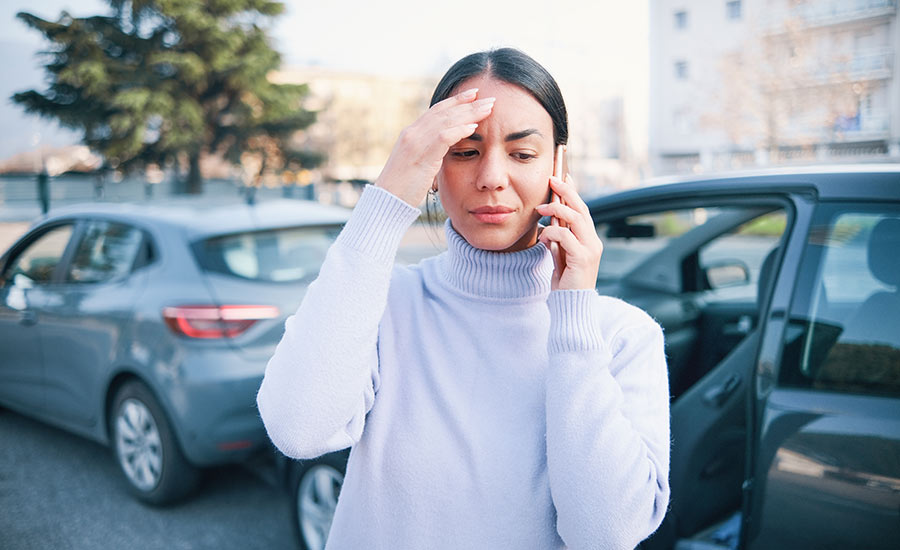 A concerned woman talking on the phone after a car accident​