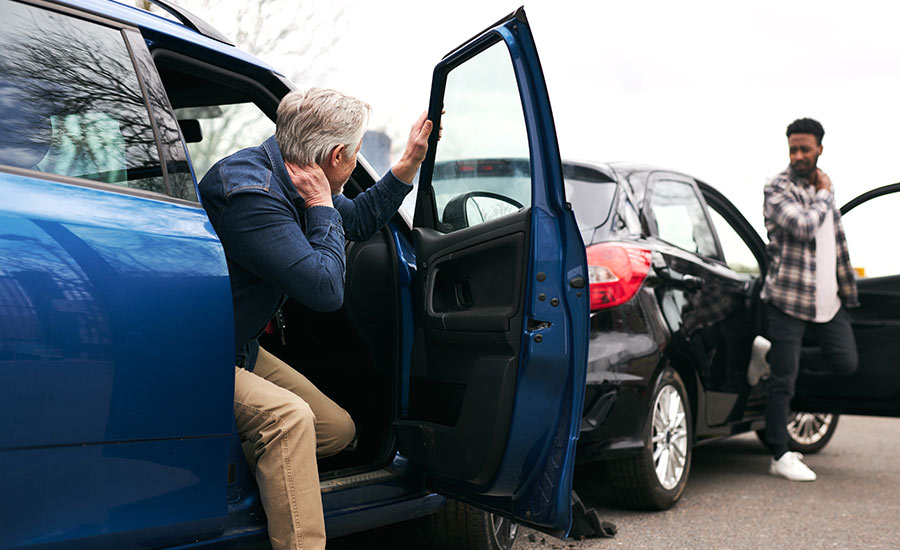 Senior and younger male drivers get out of their cars to inspect their vehicles after a rear-end collision​