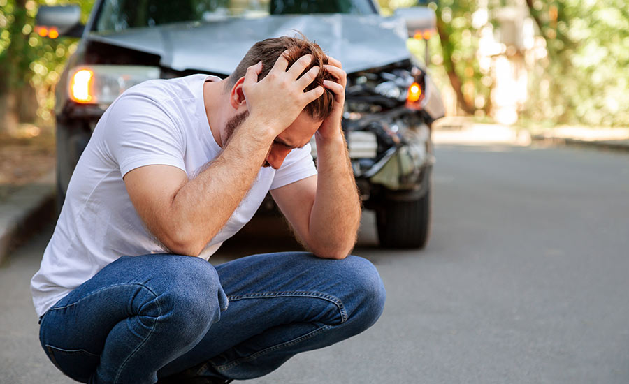 A young male driver holding his head after a car accident​